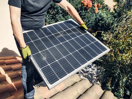 Man holding solar panel on tiles